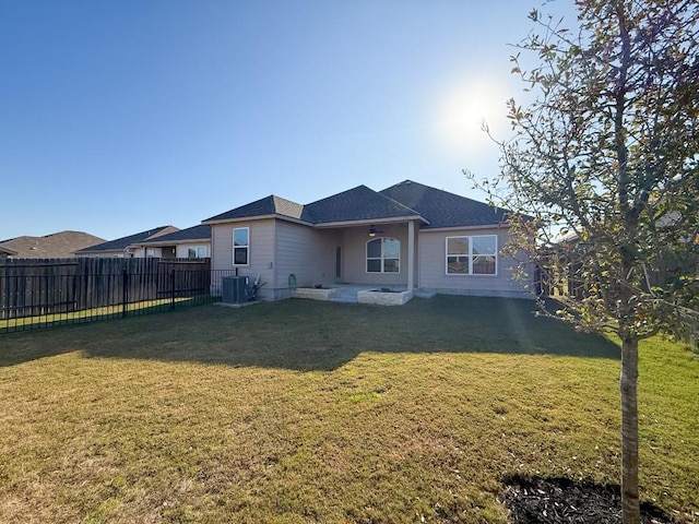 rear view of house featuring a lawn and central air condition unit