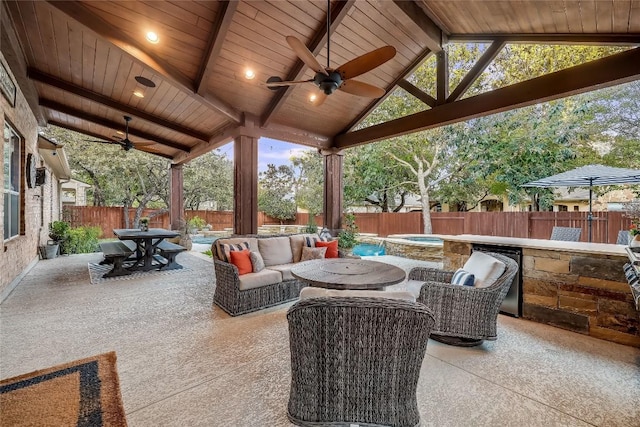 view of patio with a fenced backyard, an outdoor hangout area, an in ground hot tub, a ceiling fan, and outdoor dining space