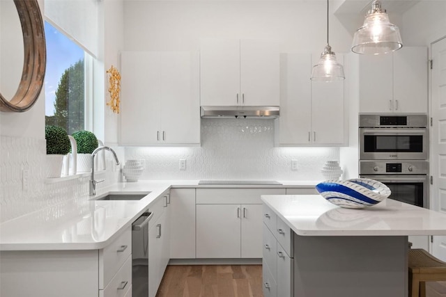 kitchen featuring white cabinetry, sink, hanging light fixtures, stainless steel appliances, and light wood-type flooring