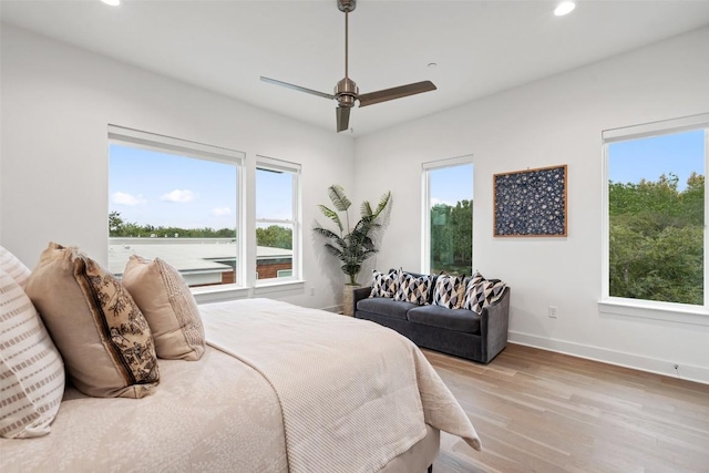 bedroom with multiple windows, ceiling fan, and light hardwood / wood-style floors