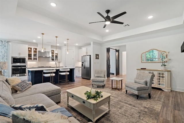 living room with a tray ceiling, ceiling fan, and dark hardwood / wood-style floors