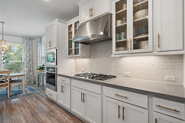 kitchen featuring decorative backsplash, appliances with stainless steel finishes, dark hardwood / wood-style flooring, pendant lighting, and white cabinetry