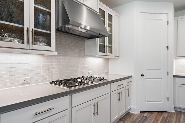 kitchen with backsplash, white cabinets, range hood, dark hardwood / wood-style flooring, and stainless steel gas cooktop