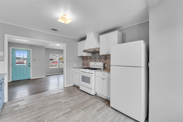 kitchen featuring custom exhaust hood, tasteful backsplash, white appliances, white cabinets, and light hardwood / wood-style flooring