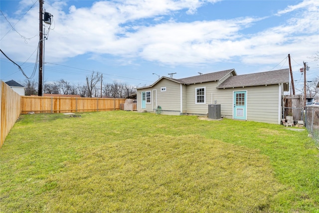 back of house with central AC and a lawn