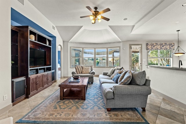 living room with light tile patterned flooring, sink, a textured ceiling, a raised ceiling, and ceiling fan