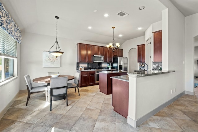 kitchen featuring kitchen peninsula, hanging light fixtures, stainless steel appliances, and vaulted ceiling