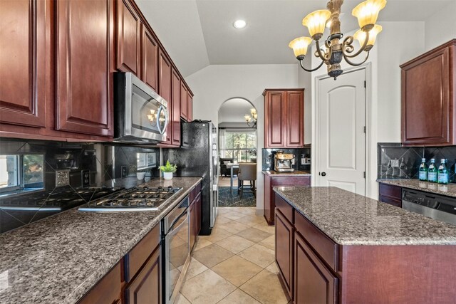 kitchen with appliances with stainless steel finishes, tasteful backsplash, vaulted ceiling, and a notable chandelier