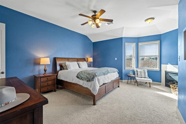 bedroom with ceiling fan, light colored carpet, and vaulted ceiling