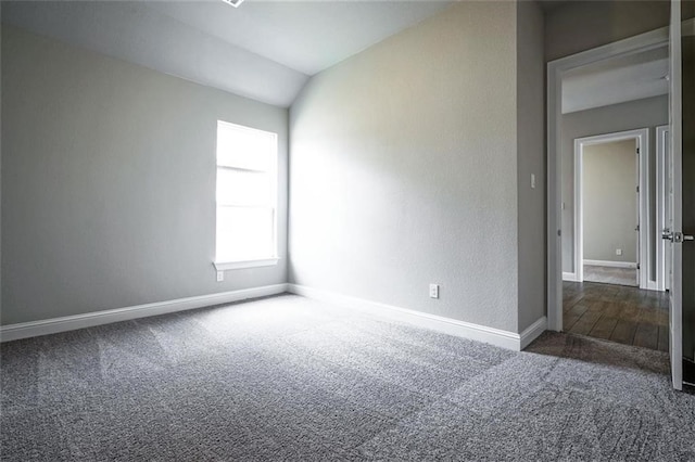 carpeted empty room with vaulted ceiling