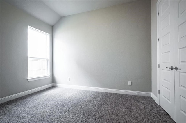 carpeted spare room featuring lofted ceiling