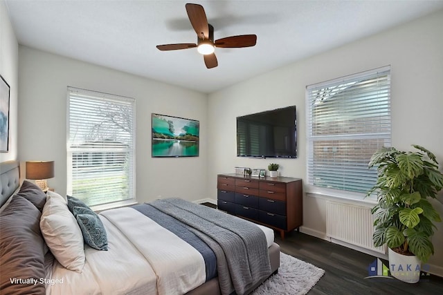 bedroom with radiator, ceiling fan, dark hardwood / wood-style floors, and multiple windows