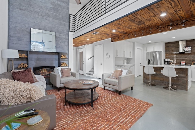 living room featuring beamed ceiling, a high ceiling, a fireplace, and wooden ceiling