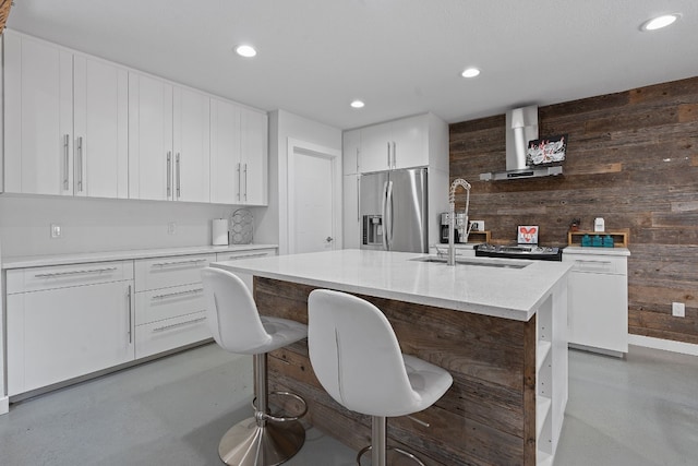 kitchen with wooden walls, stainless steel fridge with ice dispenser, an island with sink, white cabinetry, and extractor fan