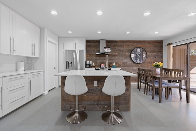 8518 Fathom Cir Unit 133, Austin, TX 78750 - kitchen with finished concrete flooring, stainless steel refrigerator with ice dispenser, recessed lighting, wooden walls, and wall chimney exhaust hood