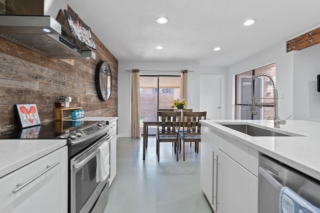 8518 Fathom Cir Unit 133, Austin, TX 78750 - kitchen featuring appliances with stainless steel finishes, wall chimney exhaust hood, a sink, recessed lighting, and concrete flooring