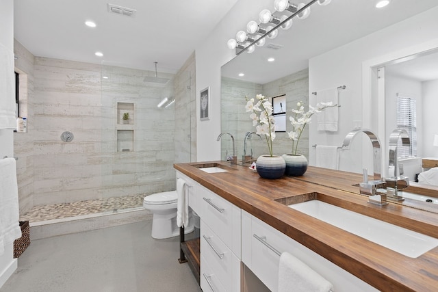 bathroom with vanity, toilet, and a tile shower