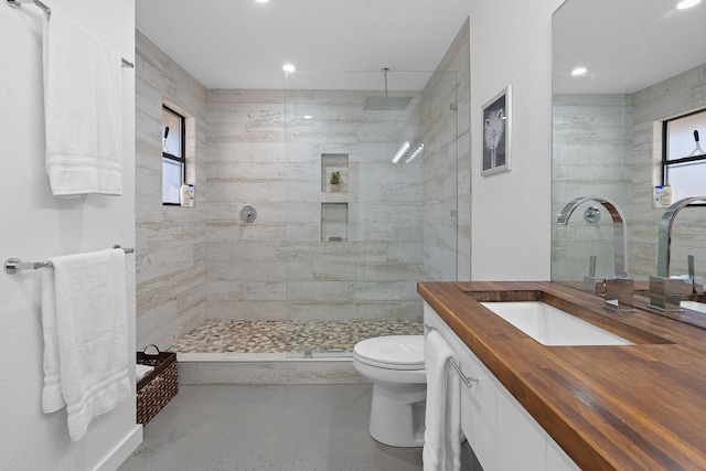 bathroom featuring a tile shower, vanity, and toilet