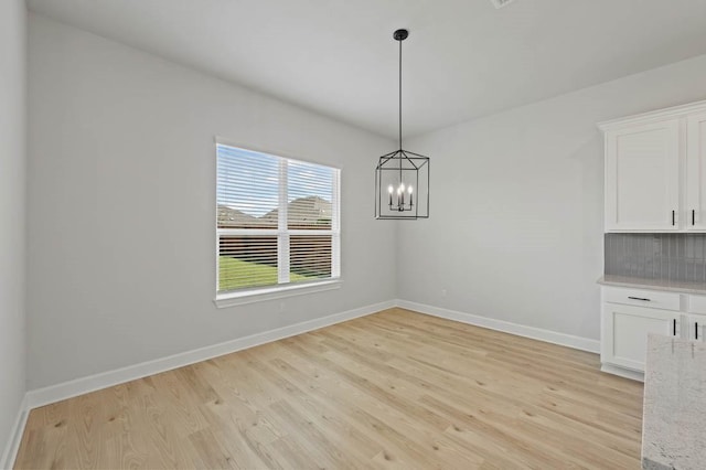 unfurnished dining area featuring light hardwood / wood-style floors and a chandelier