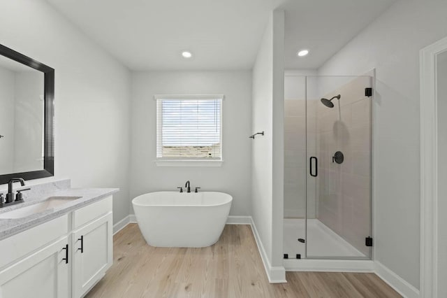 bathroom featuring hardwood / wood-style flooring, plus walk in shower, and vanity