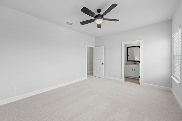 unfurnished bedroom featuring ensuite bathroom, light carpet, and ceiling fan