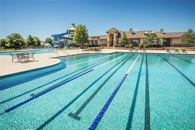 view of swimming pool featuring a water slide and a patio area