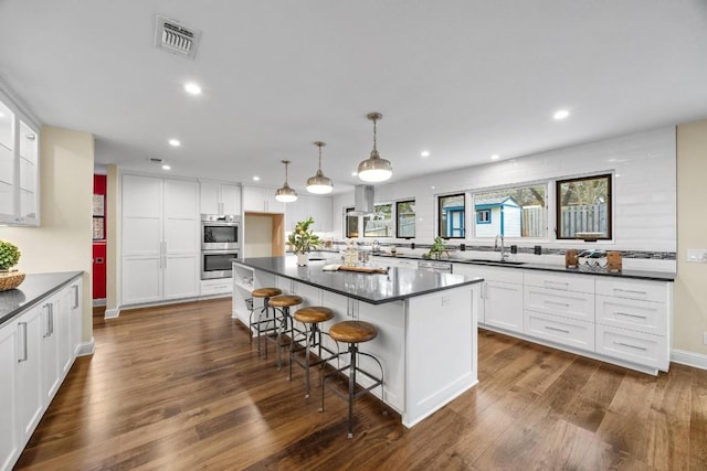 kitchen featuring white cabinets, pendant lighting, a center island, and a kitchen bar