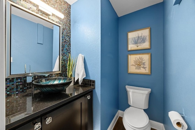 bathroom with decorative backsplash, vanity, and toilet