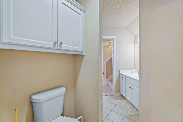 bathroom with vanity, lofted ceiling, tile patterned floors, toilet, and a textured ceiling