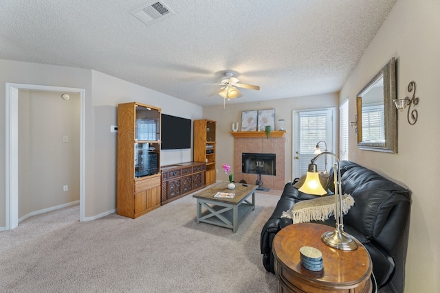 living room with carpet flooring, ceiling fan, a fireplace, and a textured ceiling