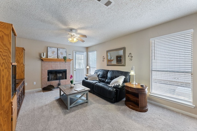 carpeted living room featuring ceiling fan, a fireplace, and a textured ceiling