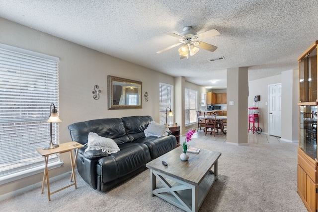 carpeted living room with ceiling fan and a textured ceiling