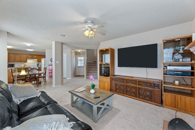 carpeted living room featuring ceiling fan and a textured ceiling