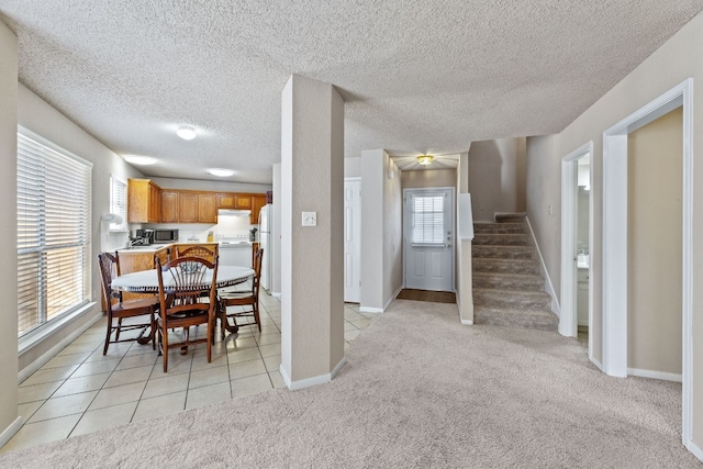 carpeted dining space featuring a healthy amount of sunlight and a textured ceiling