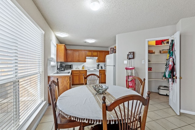 dining area featuring light tile patterned flooring, sink, and a textured ceiling