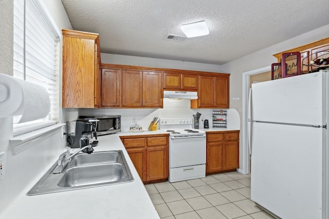 kitchen with a textured ceiling, white appliances, sink, and light tile patterned floors