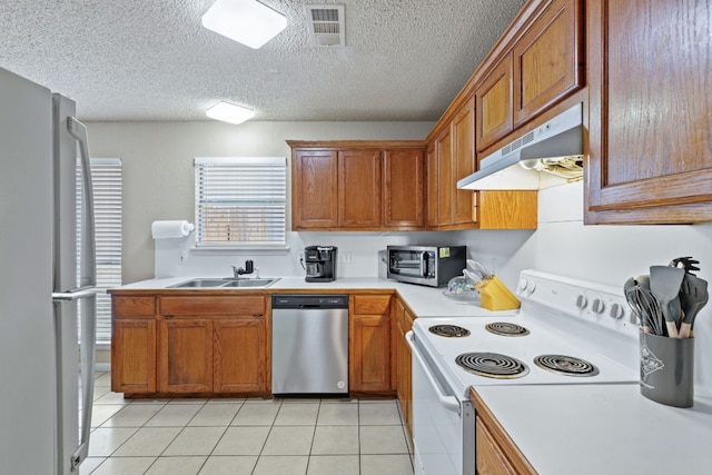 kitchen featuring sink, light tile patterned floors, a textured ceiling, and appliances with stainless steel finishes