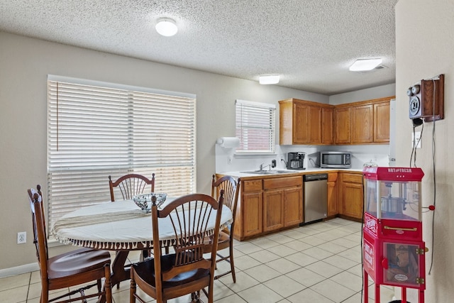 kitchen with a textured ceiling, sink, stainless steel appliances, and light tile patterned flooring