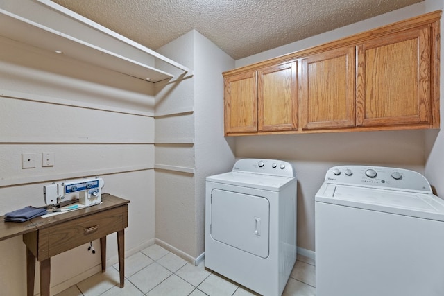 clothes washing area featuring washer and clothes dryer, light tile patterned floors, cabinets, and a textured ceiling