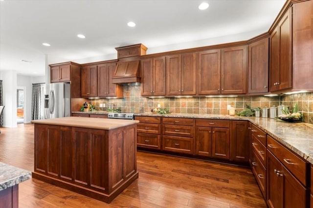 kitchen featuring backsplash, custom range hood, stainless steel appliances, a center island, and dark hardwood / wood-style floors