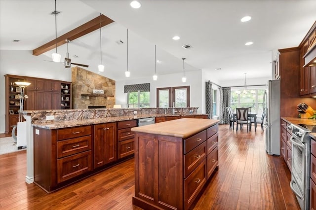 kitchen featuring appliances with stainless steel finishes, lofted ceiling with beams, hanging light fixtures, and a large island