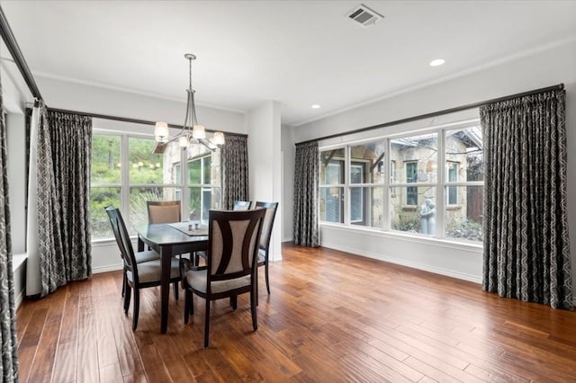 dining room with crown molding, hardwood / wood-style floors, a healthy amount of sunlight, and an inviting chandelier