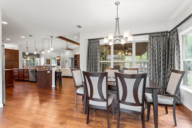 dining area featuring vaulted ceiling with beams, ceiling fan with notable chandelier, dark wood-type flooring, and sink