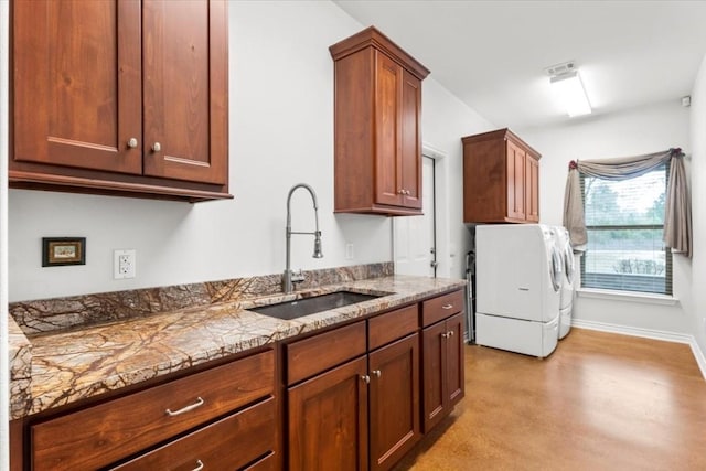 kitchen featuring washer and dryer, light stone countertops, and sink