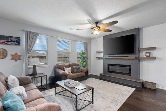 living room featuring a textured ceiling, dark hardwood / wood-style floors, ceiling fan, and a fireplace