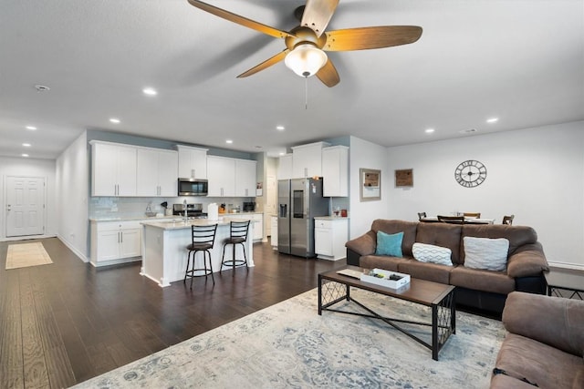 living room featuring ceiling fan and dark wood-type flooring