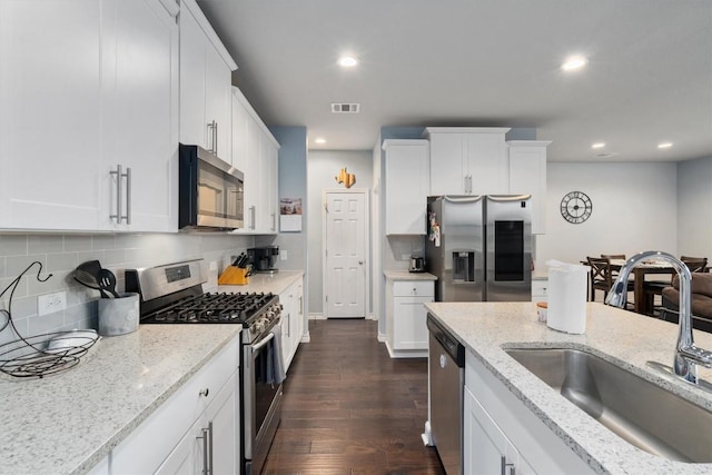 kitchen featuring sink, dark hardwood / wood-style floors, appliances with stainless steel finishes, light stone counters, and white cabinetry