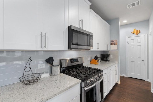 kitchen featuring backsplash, light stone counters, stainless steel appliances, dark hardwood / wood-style floors, and white cabinetry