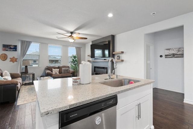 kitchen featuring light stone countertops, stainless steel dishwasher, sink, a center island with sink, and white cabinets