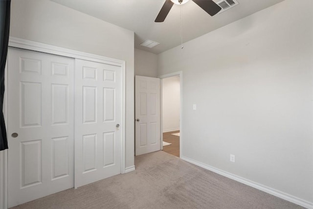 unfurnished bedroom featuring ceiling fan, light colored carpet, and a closet